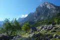 Eine einfache Berghütte in einer bergigen Landschaft mit einem hohen Gipfel im Hintergrund.