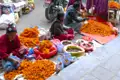 Marktstand mit orangenen Ringelblumen und anderen Waren, betreut von Frauen.