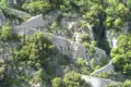 Historische Steinmauern in einer bewaldeten Berglandschaft.