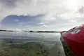 Rotes Kajak im ruhigen Wasser mit Inseln im Hintergrund.