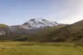 Panoramablick auf einen schneebedeckten Berg und das grüne Tal.