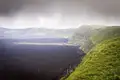 Kontrast zwischen dem dunklen Lavafeld und der grünen Vegetation.
