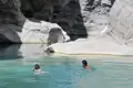 Zwei Personen schwimmen in einem natürlichen Pool zwischen Felswänden.