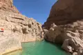 Wasserfall und türkisfarbener Pool in einer felsigen Schlucht.
