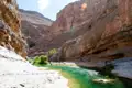 Smaragdgrüner Fluss in einer Schlucht mit steilen Felswänden und hellem Untergrund.
