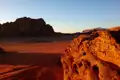 Roter Sand und Felsformationen in der Wüste bei Sonnenuntergang.