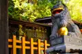 Steinerner Löwe mit goldener Kugel am Eingang eines traditionellen japanischen Gebäudes.
