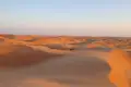 Wellenförmige Sanddünen erstrecken sich bis zum Horizont.