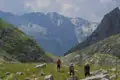 Drei Wanderer auf einem Bergpfad mit Blick auf die schneebedeckten Gipfel.