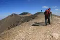 Wanderer auf einem felsigen Bergkamm mit Blick auf weitere Gipfel.