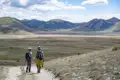 Zwei Wanderer auf einem Wanderweg mit Blick auf eine hügelige Landschaft.