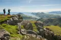 Wanderer auf einem Berggipfel mit Blick auf die Küstenlandschaft.