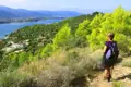 Wanderer auf einem Küstenpfad mit Blick auf das Meer und die Berge.