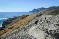 Wanderer auf einem felsigen Küstenpfad mit Blick auf das Meer.