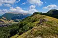 Landschaftsaufnahme von bewaldeten Hügeln und Bergen im Hintergrund.