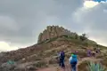 Wandergruppe auf einem Pfad in Richtung einer felsigen Bergformation.