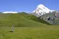 Wanderer in einer Berglandschaft mit schneebedecktem Gipfel im Hintergrund.