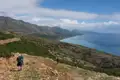 Wanderer auf einem Bergpfad mit Blick auf die Küste und das Meer.