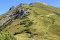 Wanderer pausieren auf einem grünen Berghang während einer Bergwanderung.