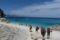 Wanderer erreichen einen weißen Sandstrand am Meer.