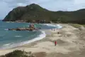 Abgelegener Strand mit Hügelkette im Hintergrund.
