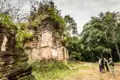 Besichtigung einer alten Tempelruine während einer Reise. Die Ruine zeigt verwitterte Ziegel und üppige Vegetation.