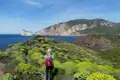 Wanderer auf einem Küstenpfad mit Blick auf das Meer und Felsformationen.