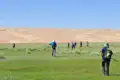 Wandergruppe in einer grünen Oase vor dem Hintergrund von Sanddünen.