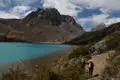 Wanderer auf einem Pfad neben einem türkisfarbenen See in den Bergen.