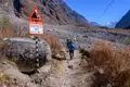 Wanderer in Lawinenrisikogebiet im Himalaya. Ein Warnschild zeigt die Gefahr an.