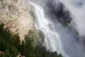 Wasserfall, der von einer Klippe stürzt und teilweise von Nebel verdeckt wird.