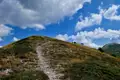 Wanderweg auf einem Hügel unter blauem Himmel mit Wolken.