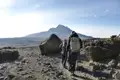 Zwei Wanderer auf einer Bergtour, die felsiges Terrain durchqueren und auf den Gipfel zusteuern.