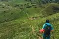 Wanderer mit Rucksack und Wanderstöcken auf einem Bergpfad.