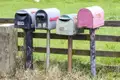 Vier Briefkästen mit den Nummern 1110F, 111A, 1110E und 1108 an einem Holzzaun.