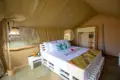 Innenansicht eines Safari-Zeltes mit Bett, Nachttischen und einem Regal.