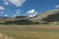 Panoramablick auf ein grünes Tal mit Bergen im Hintergrund.