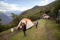Campingplatz in den Bergen mit mehreren Zelten und Reisenden.