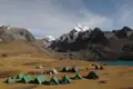 Campingplatz in den Bergen mit Blick auf einen See und schneebedeckte Gipfel.