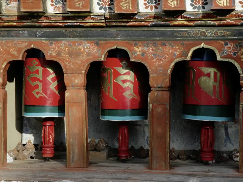 Ausf unserer Klassik-Studienreise durch das Königreich Bhutan kommen wir an zahlreichen Klöstern und Tempeln vorbei, an denen Gebetsmühlen in die Fassaden eingelassen sind. Die rote Farbe bedeutet Glück.