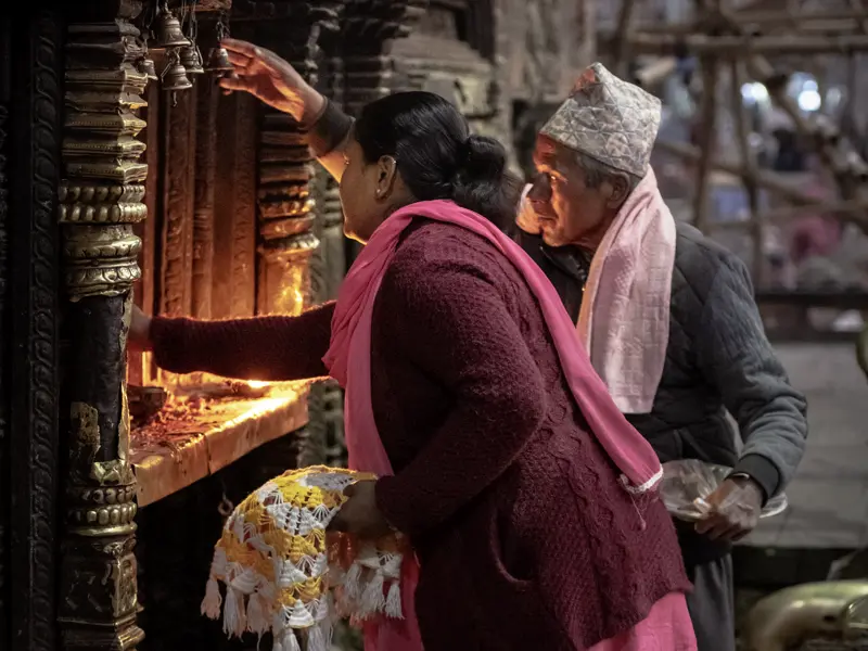 Auf unserer Studienreise Nepal - am Thron der Götter begegnen wir überall der lebendigen Spiritualität der Nepalesen. Hier entzünden Gläubige in der Gebetsnische eines Tempels Butterlampen und bitten die Götter um ihren Segen.
