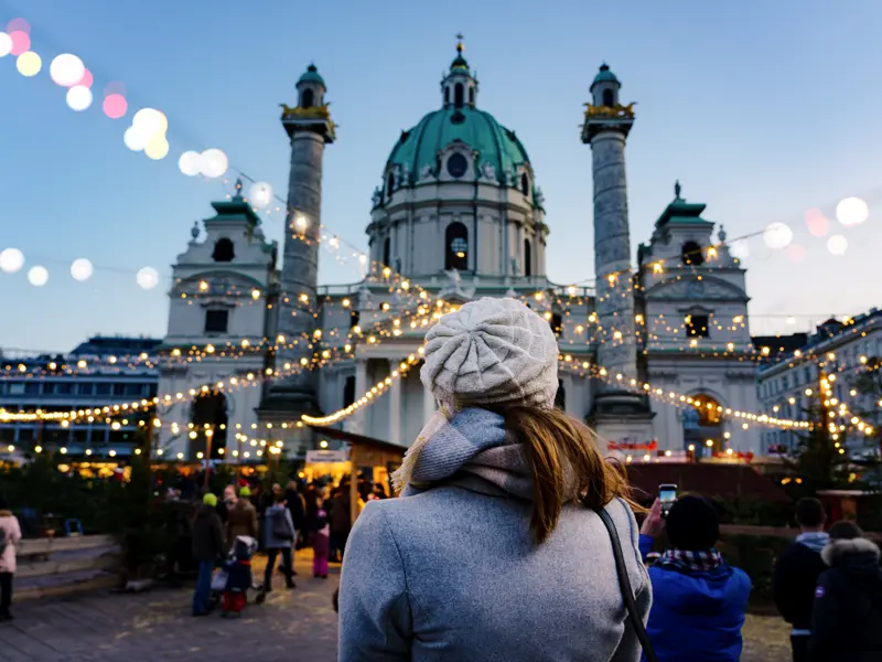 Auf unserer me&more Silvesterreise nach Wien sehen wir auch die Karlskirche. An kälteren Wintertagen ist ein Glaserl Glühwein eine willkommene Gelegenheit, um sich aufzuwärmen.