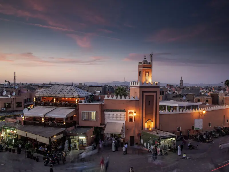 Auf unserer Singlereise durch Marokko erleben wir den Hauptplatz Djemma el-Fna (Gauklerplatz) in Marrakesch und blicken im Abendlicht von einer der vielen Teehaus-Terrassen rund um den Platz auf das Markttreiben.