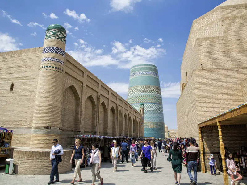 Auf unserer Studienreise durch Usbekistan führt Sie Ihre Reiseleiterin durch die Altstadt von Chiwa zum halbfertigen Minarett.