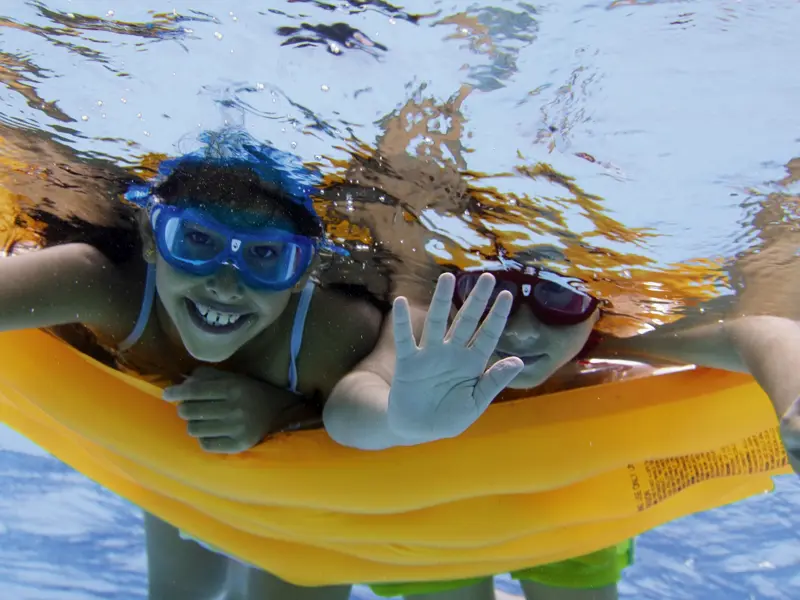 Auf der Familien-Studienreise nach Griechenland haben die Kinder wie hier beim Schwimmen und Tauchen auf einer Luftmatratze im Meer viel Spaß.