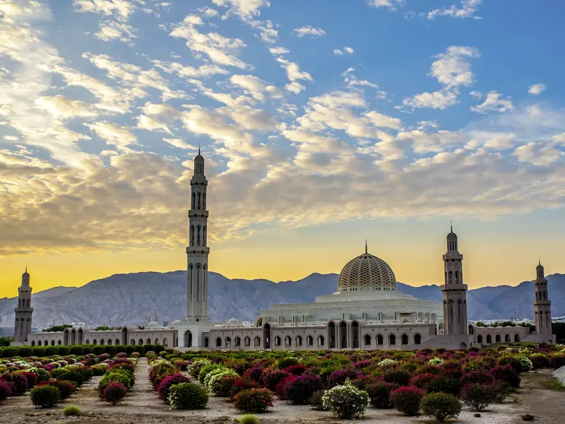 Wir sehen während der umfassenden Studienreise durch den Oman die Sultan-Qaboos-Moschee in Maskat vor bergigem Hintergrund.