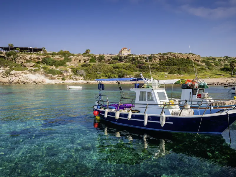 Unsere Reise führt uns auch in den Küstenort Paphos, wo die Cafés am Hafen zu einer Pause einladen und wir die Fischerboote im glasklaren Wasser beobachten können.