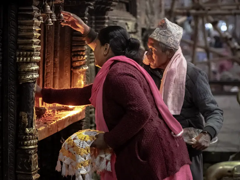 Auf unserer Studienreise Nepal - am Thron der Götter begegnen wir überall der lebendigen Spiritualität der Nepalesen. Hier entzünden Gläubige in der Gebetsnische eines Tempels Butterlampen und bitten die Götter um ihren Segen.