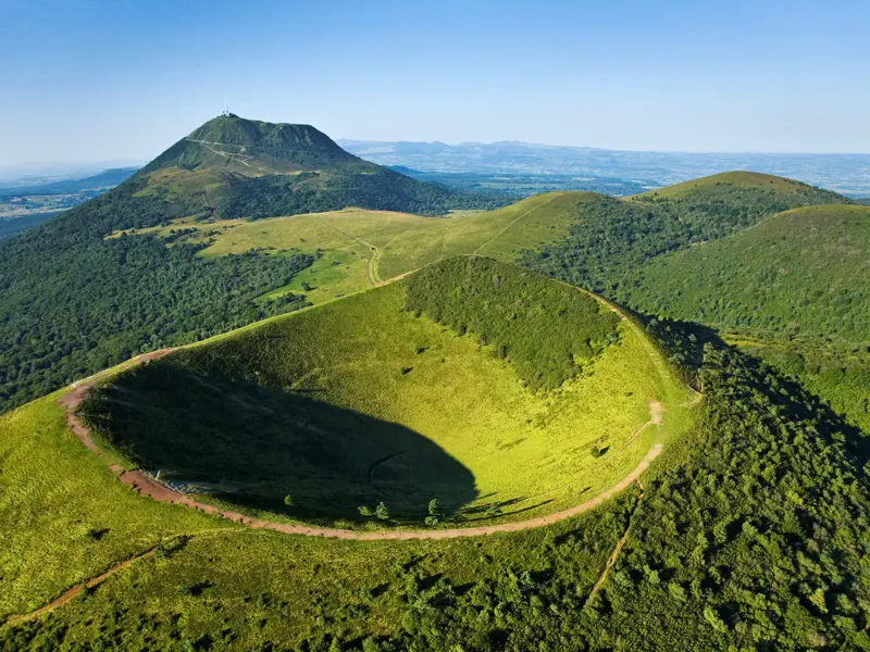 Auf unserer Studienreise Auvergne-Périgord - das grüne Herz Frankreichs blicken wir über die sattgrün bewaldeten Vulkane der Auvergne, im Hintergrund der berühmteste von ihnen: der Puy de Dome.