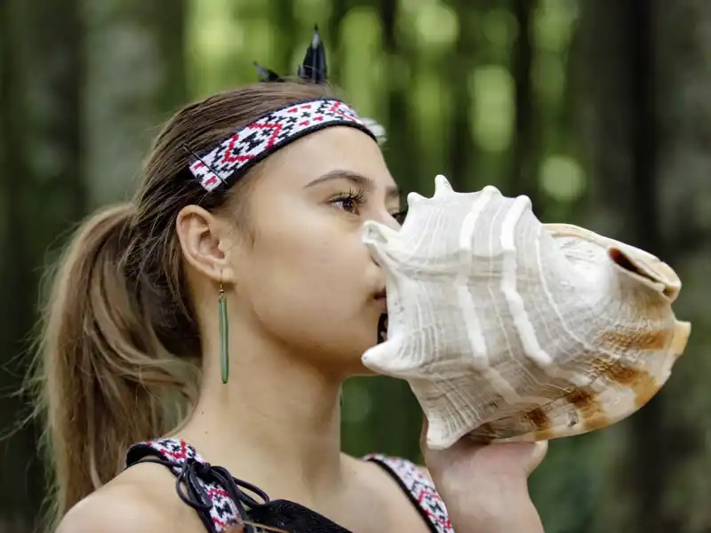 Auf unserer Studienreise Australien-Neuseeland - zum Kennenlernen begegnen wir auch den Maori, den Ureinwohnern Neuseelands. Zur Begrüßung wird ein Ton auf einer Muschel gespielt, hier von einer jungen Frau.